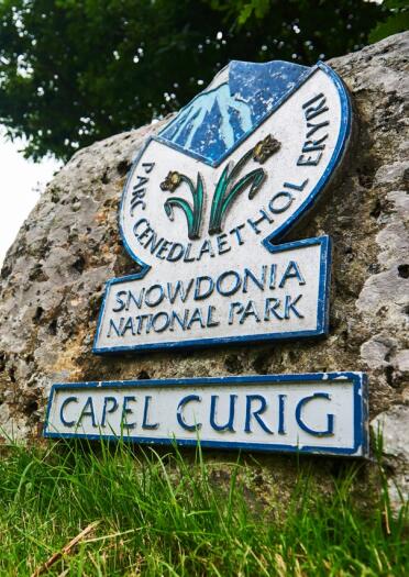 A plaque on a stone wall which reads Capel Curig, Snowdonia National Park.