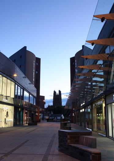 A shopping centre pedestrianised street during nightfall.