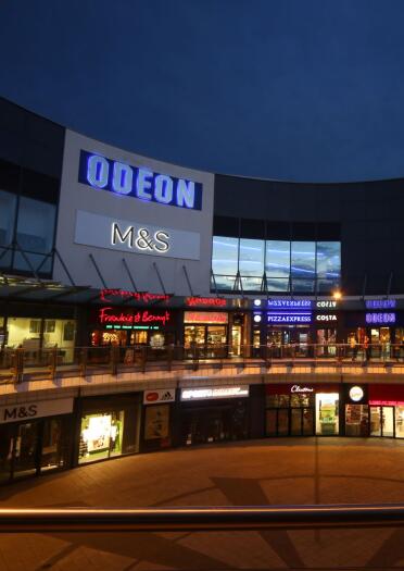 A shopping complex and cinema lit up at night.