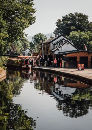 People waiting besides a canal to board a boat for a trip.