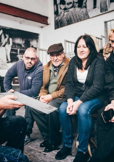 A group of people watching a demonstration on slate splitting.