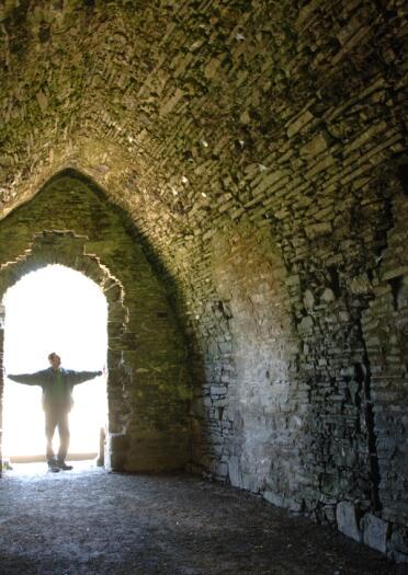 Silhouette of a man looking inside and ancient stone walled dungeon