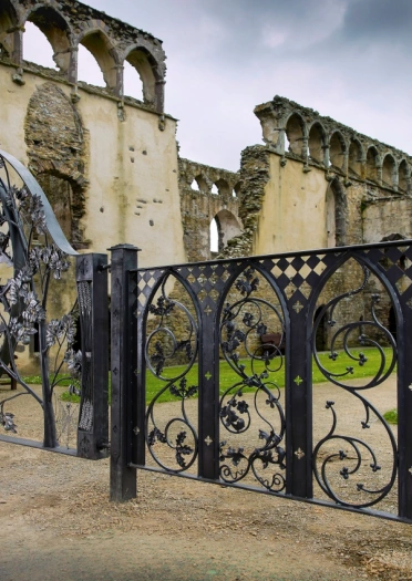 Decorative wrought iron gate entrance looking onto ruins of a palace.