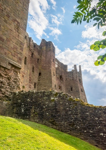 Looking up at castle walls from a grassy embankment.