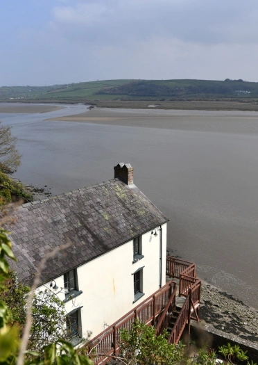 A white boathouse looking over the estuary.