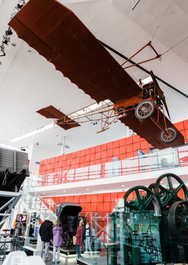 An old plane on display with people looking at other exhibits at a museum.