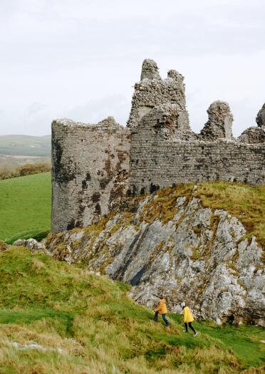 People walking by a ruined castle on a hill