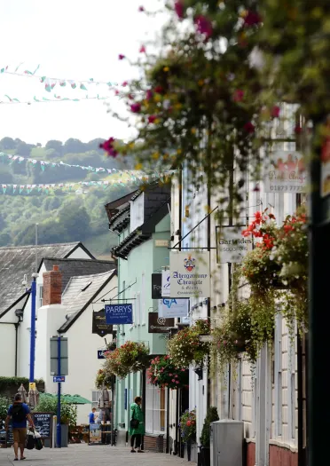 A colourful shopping street with signage outside each shop in Abergavenny.