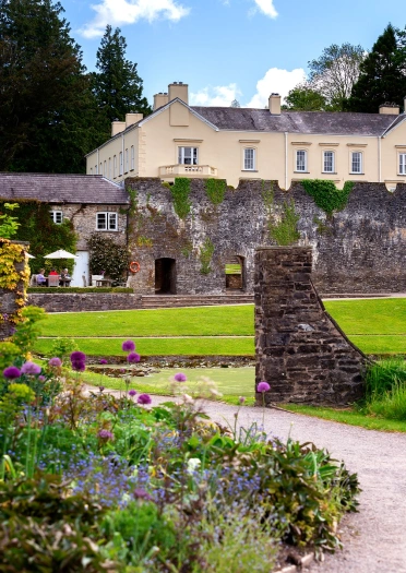 A grand walled mansion amongst colourful gardens.