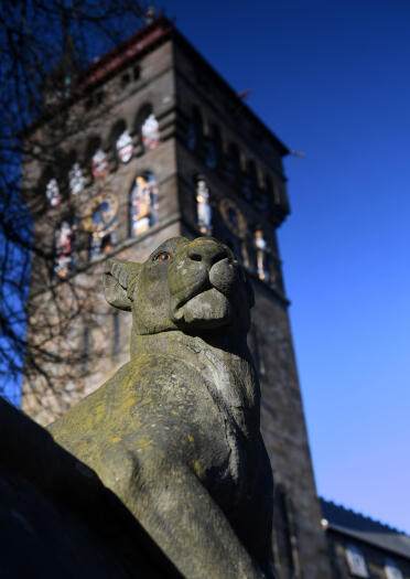 Cardiff Castle clock tower with a stone animal in front.