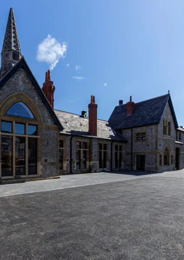 An old school building with barrels outside spelling Penderyn Distillery.