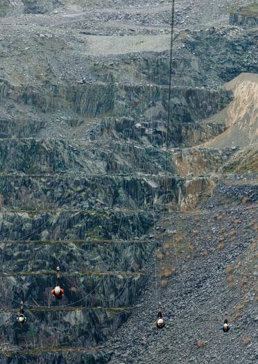 People ziplining through a disused slate quarry.