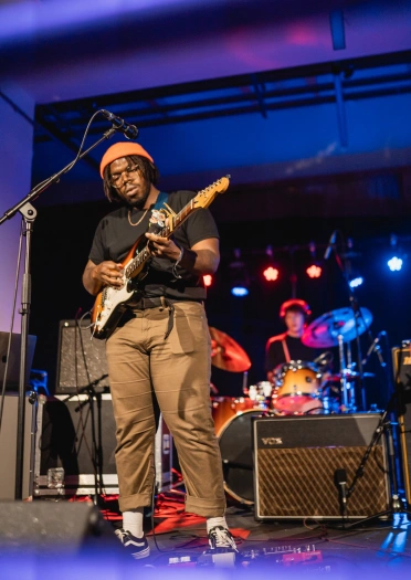 A guitarist and drummer on stage performing.