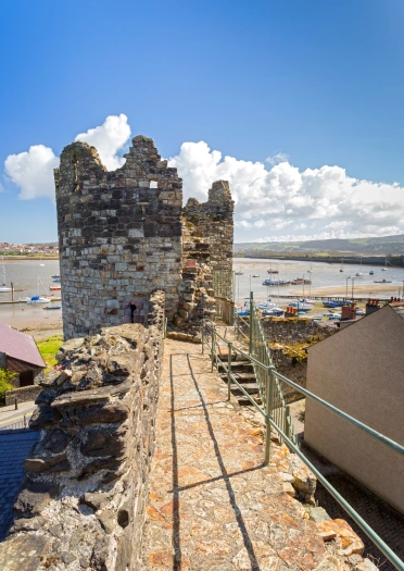 Castle town walls walkway leading towards a turret with views toward the harbour.