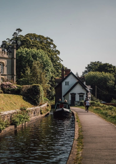 People walking on a canal towpath with a narrowboat cruising by.