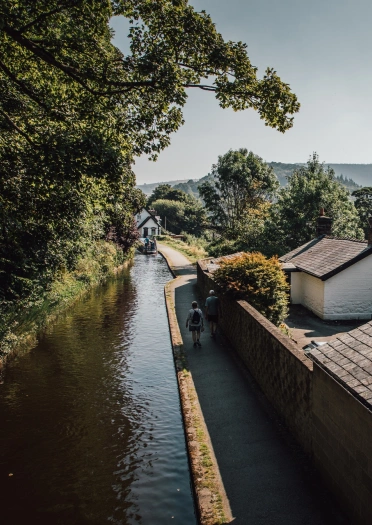 People walking along a towpath next to a canal.