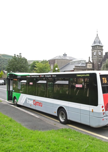 A public service bus at a bus stop next to a beautiful building.
