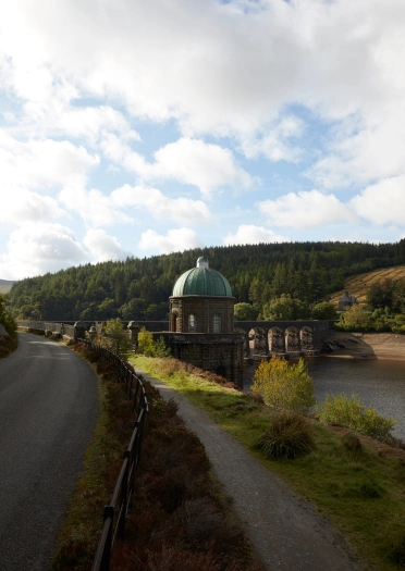 A road running alongside a reservoir and dam.