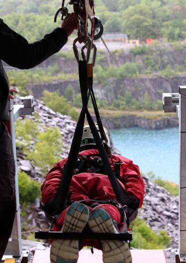 A person in a harness about to launch down a zip wire over a quarry and reservoir.