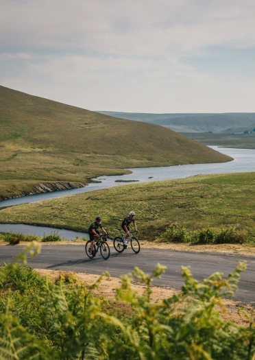 Cyclists pedalling around a bending river.