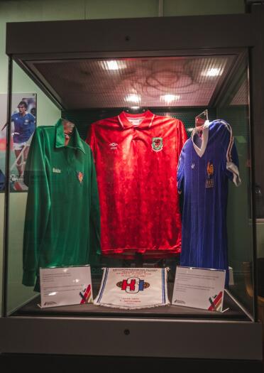 Football shirts in glass casings within a museum.