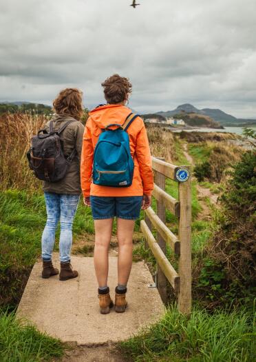 Walkers on the coastal path with a castle beyond.