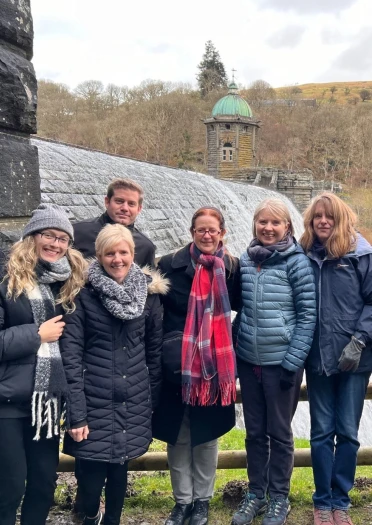 Group of people smiling at the camera by a dam with water cascading.