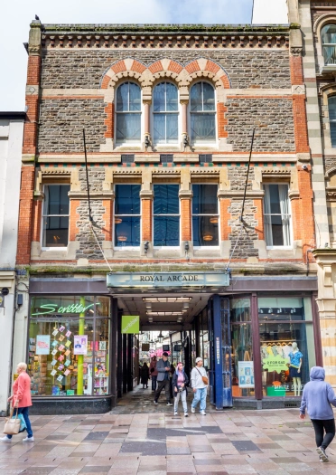 Shoppers near the entrance to a Victorian shopping arcade in a city centre.