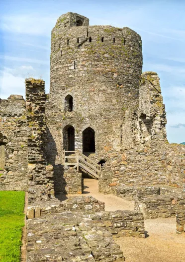 A tower and stone wallls of a castle.