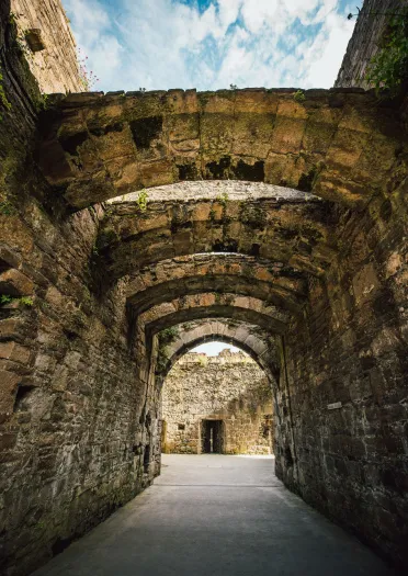 Stone arches over a walkway inside a castle.