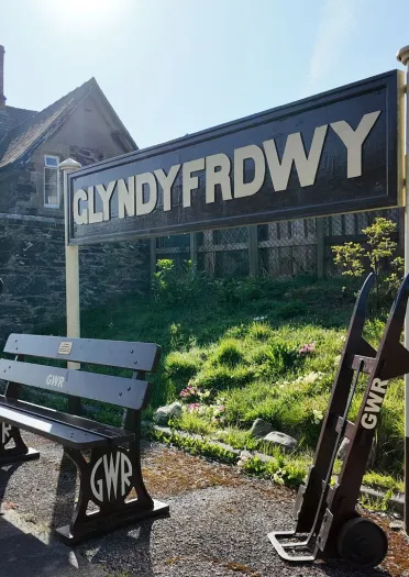 A quaint station house, bench and sign on a platform of a steam train route.