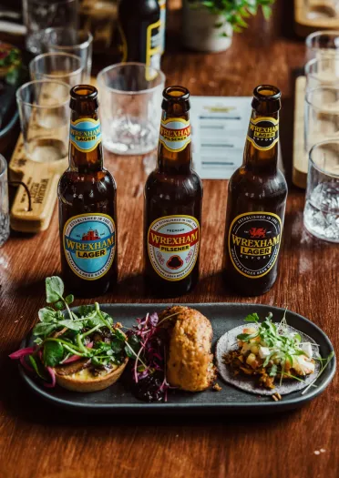 A plate of food alongside bottles of lager.