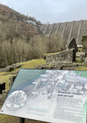 Information board showing the former lead mines with a dam beyond.