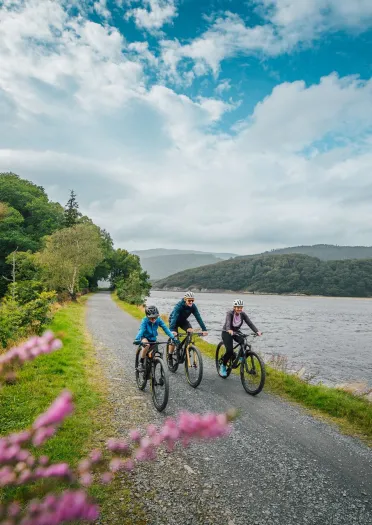 Family of cyclists passing a lake.