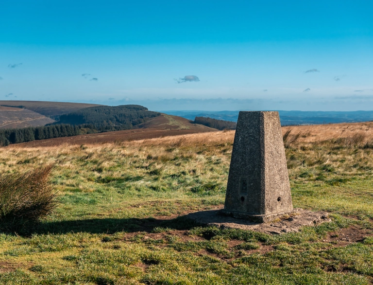 A stone plinth at the top of a mountain with far reaching views.