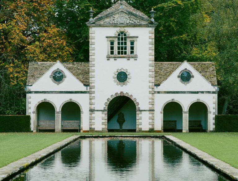 The summer house reflecting in the pool with water lillies at Bodnant Garden.