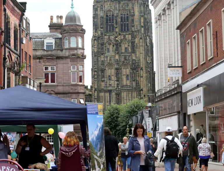 A cathedral at the end of a shopping street in a city centre.