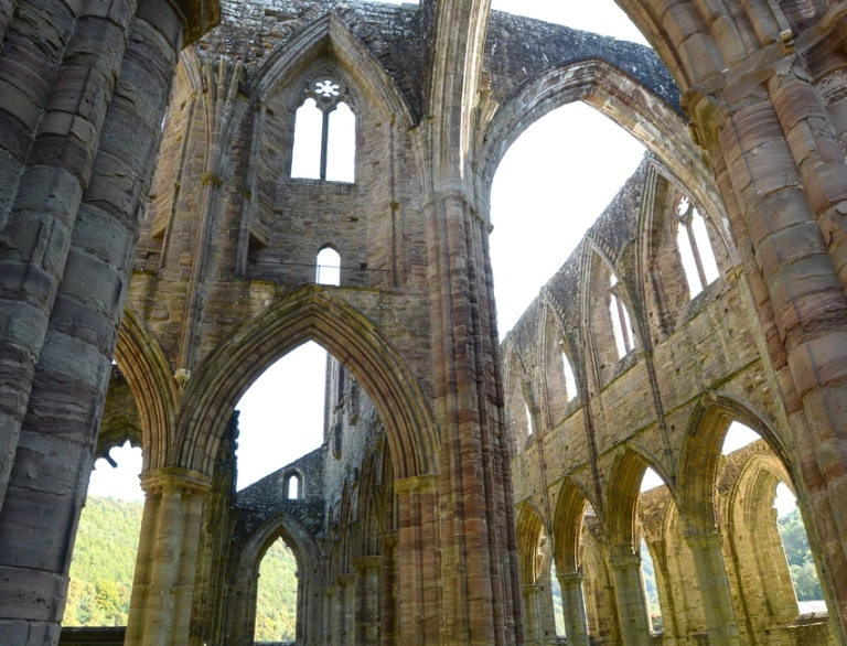 Inside a derelict abbey with magnificent arches and arched window frames.