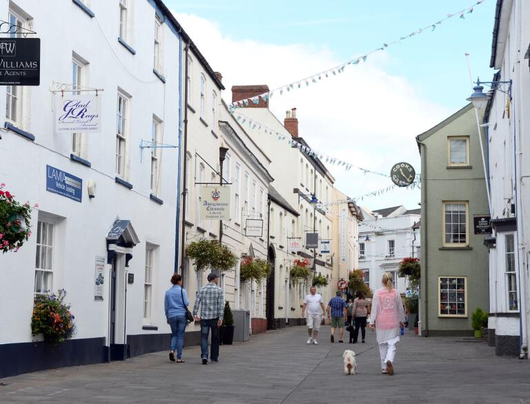 People walking down a pedestrianised shopping street in Abergavenny.