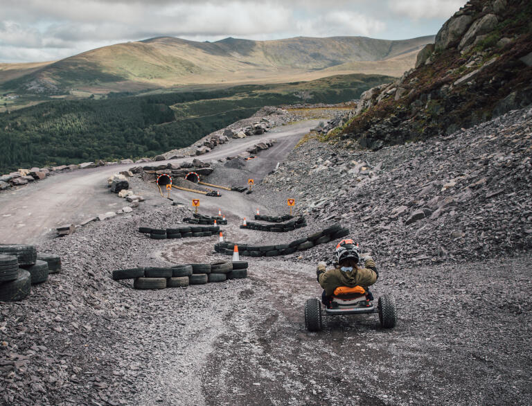 A go cart travelling down a slalom obstacle course of tyres and tunnels at a former slate quarry.