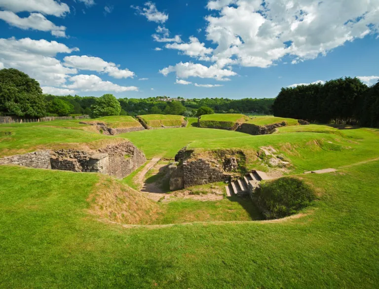 Remains of the Roman amphitheatre amongst lawned embankments.