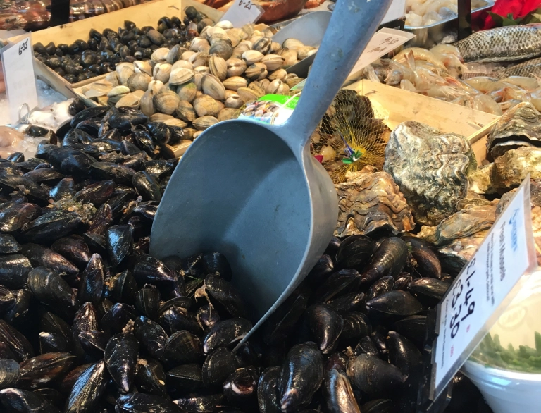 A market stall with cockles, fish and shellfish on display.