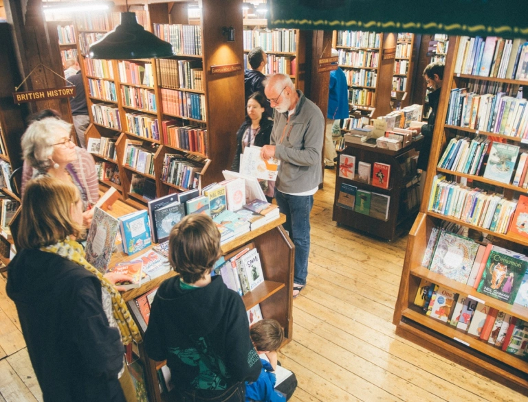 People in a bookshop, amongst shelves full of books.