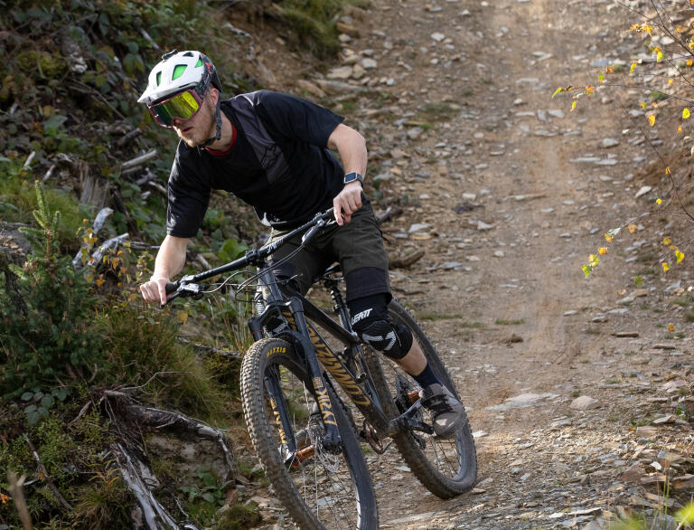 A mountain biker riding downhill on a humped dirt track.