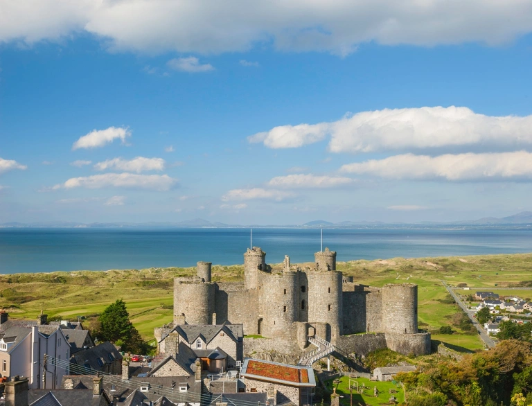 A castle and golf course with the sea beyond.