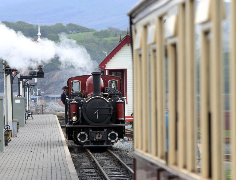 A steam train travelling along a station to be attached to a carriage.