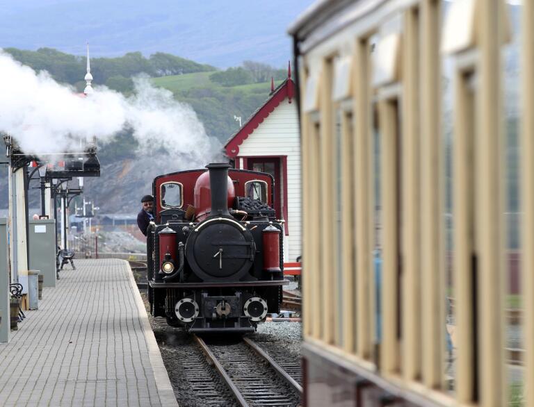 A steam train travelling along a station to be attached to a carriage.