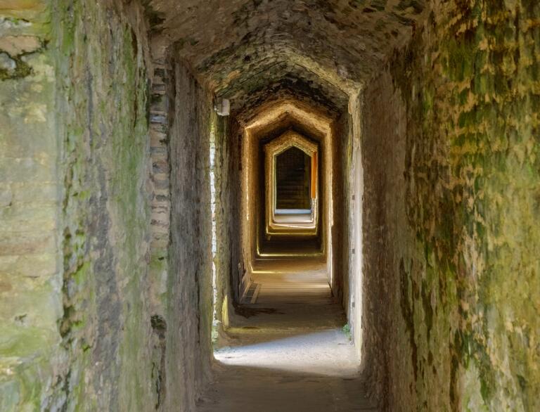 A long stonebrick passageway in a castle.