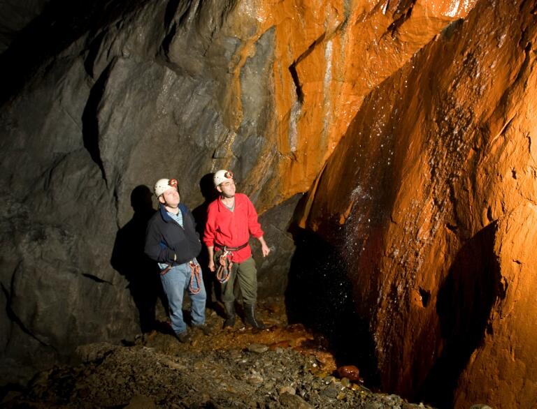 Two people wearing hard hats looking up in a brightly lit mine.