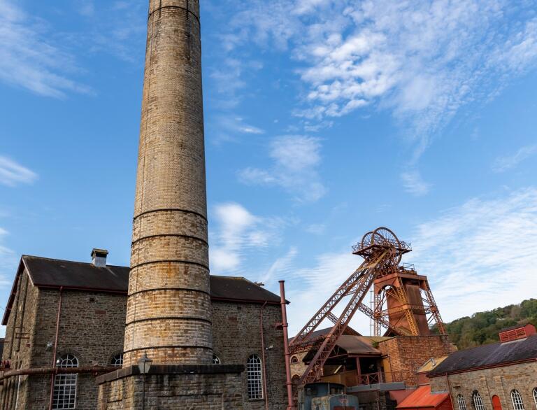 A chimney and winding wheel at a coal mining experience.